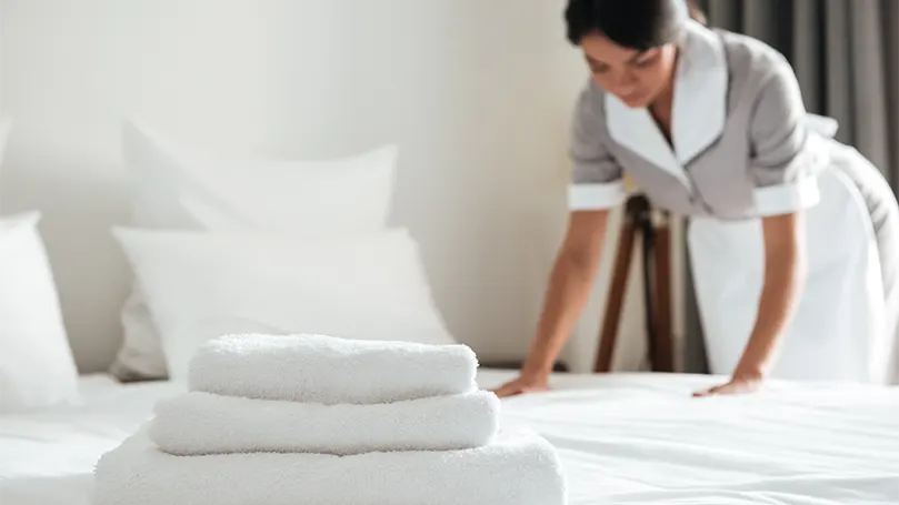 Image d'une femme de chambre faisant un lit dans un hôtel.