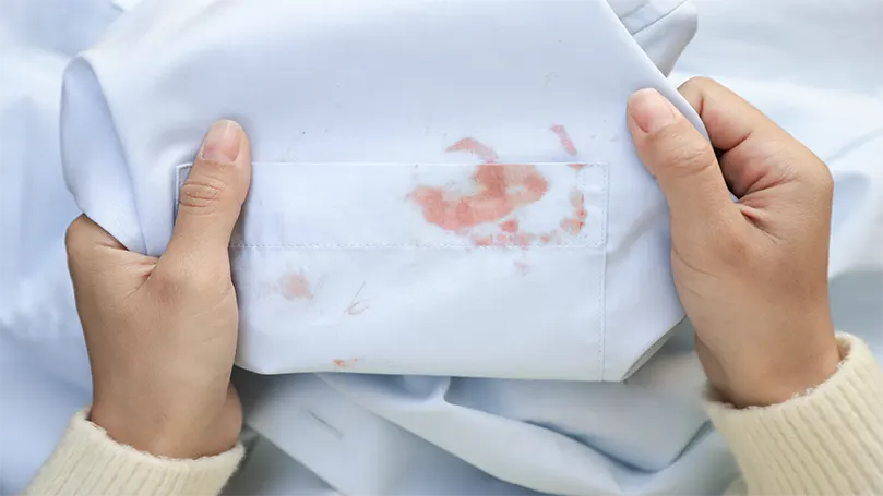 une femme tenant un drap dans ses mains couvertes de taches de sang.