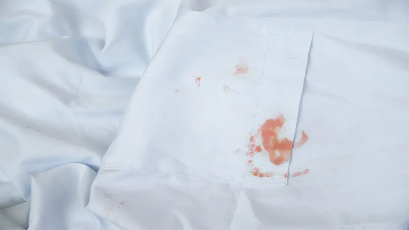 une tache de sang sur des draps blancs.