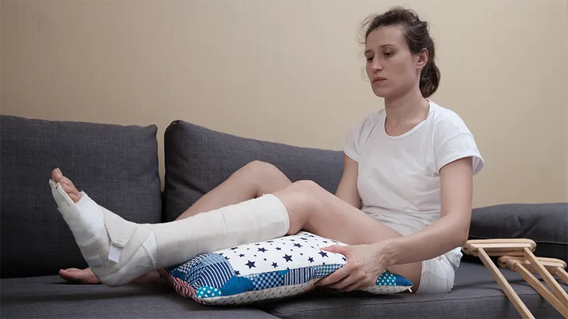 Image d'une femme sur un canapé avec un oreiller sous son genou.