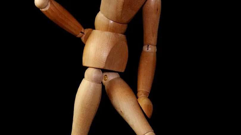 une poupée en bois simulant une position avec une douleur sciatique