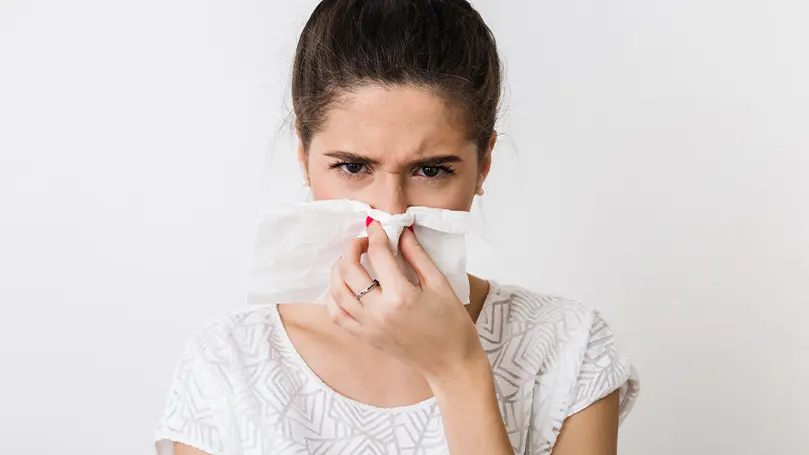 Une femme se mouche en raison d'allergies