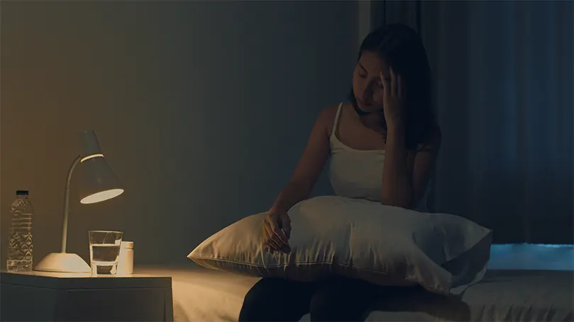 Image d'une femme au lit la nuit, incapable de dormir en raison d'un manque de mélatonine.