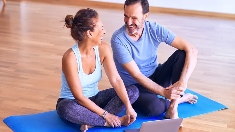 Image de deux personnes se reposant sur un tapis de yoga après avoir fait de l'exercice et avoir été actives.