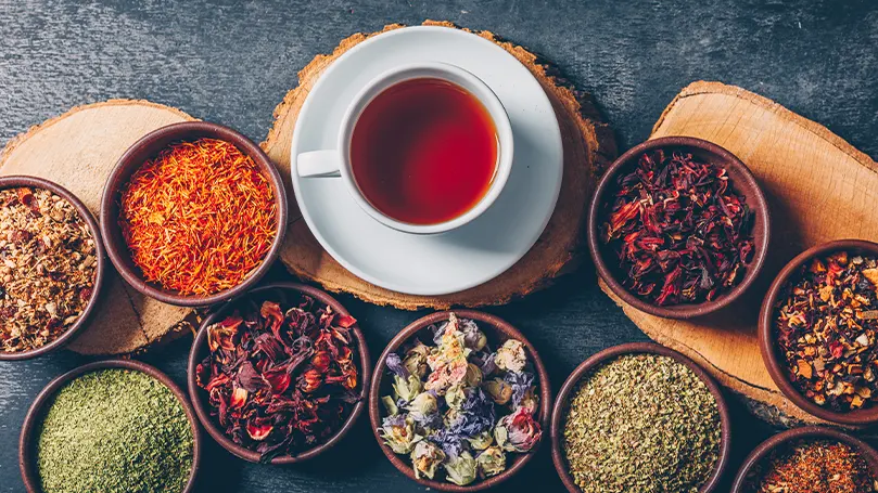 Image d'une tisane dans une tasse entourée d'autres thés sains.