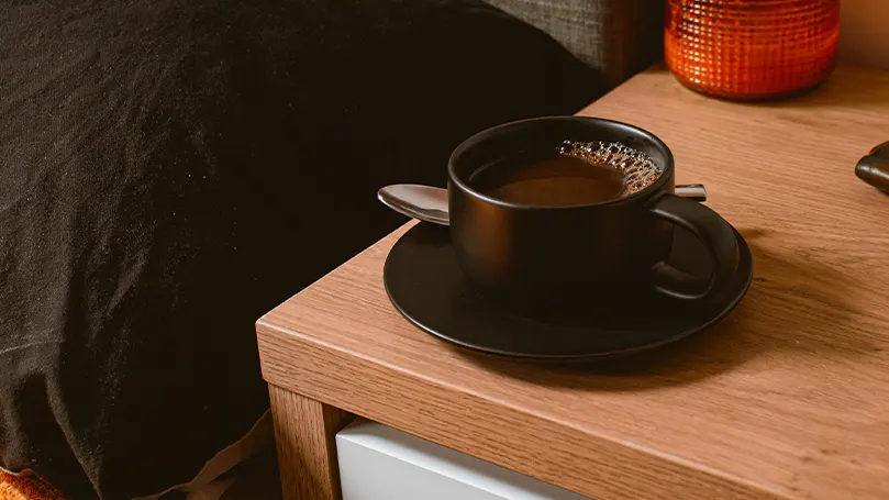 Image d'une table de nuit sur laquelle est posée une tasse de café.
