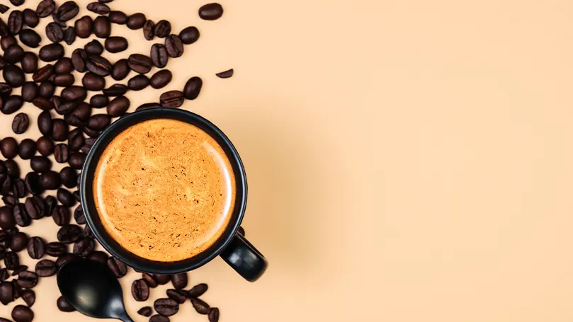 Image d'une tasse de café avec des haricots de café sur le côté.
