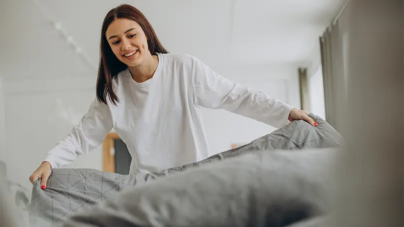 Image d'une femme heureuse faisant son lit.