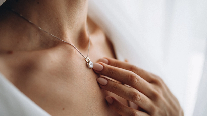Image d'une femme avec un collier touchant le pendentif