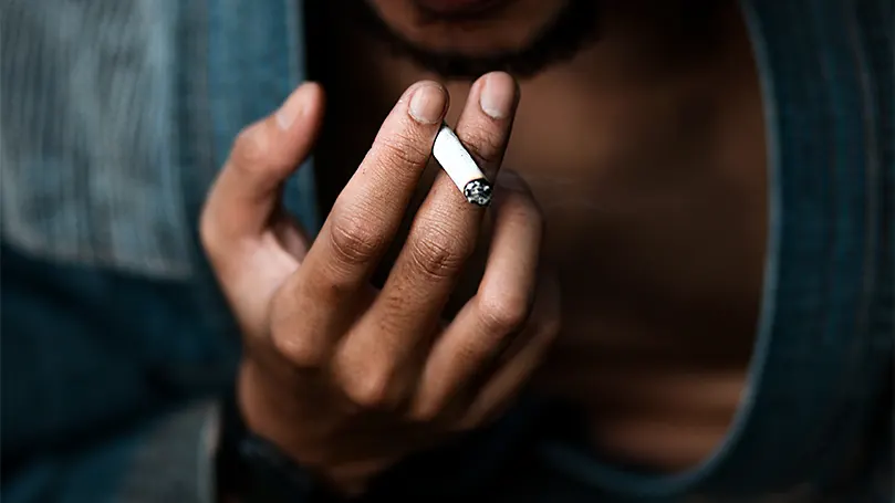 Image d'une personne tenant une cigarette.