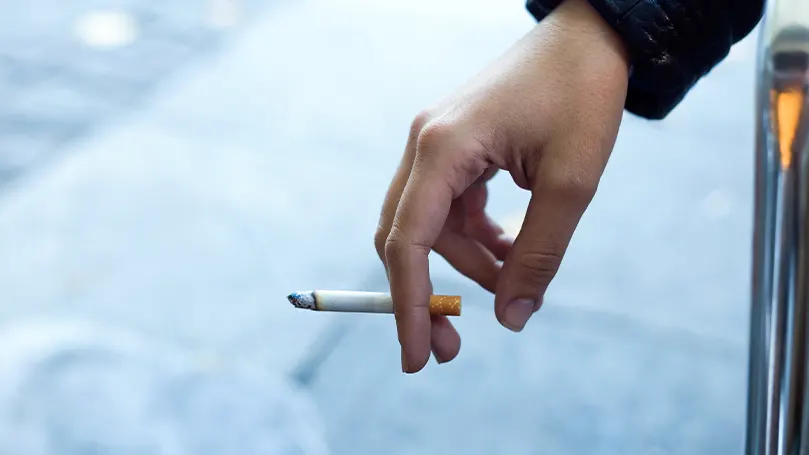 Image d'une main tenant une cigarette.