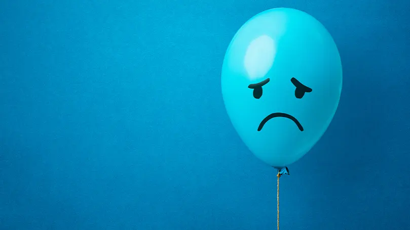 Image d'un ballon bleu sur lequel est dessiné un visage triste.