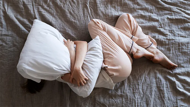 Une personne anxieuse se blottit contre son oreiller et tente de s'endormir.