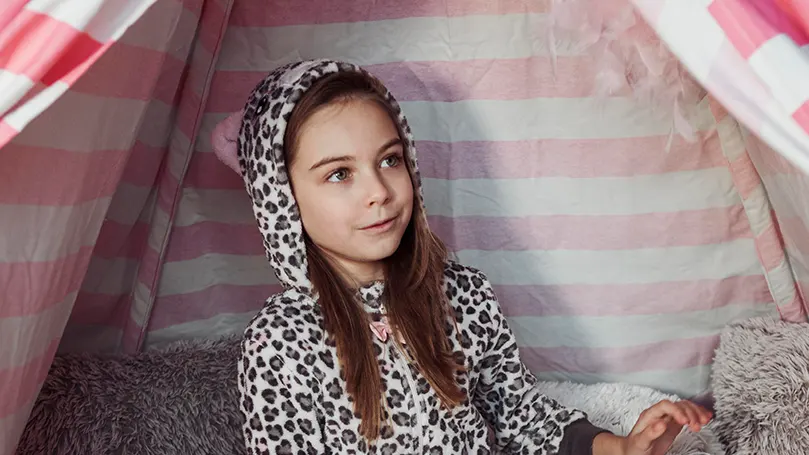 Une image d'une fille en pyjama sous une grande couverture fort