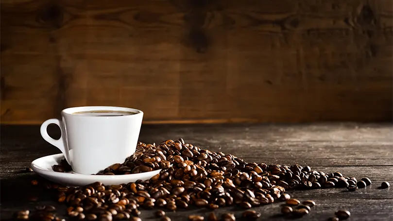 Une tasse de café avec des grains de café tout autour