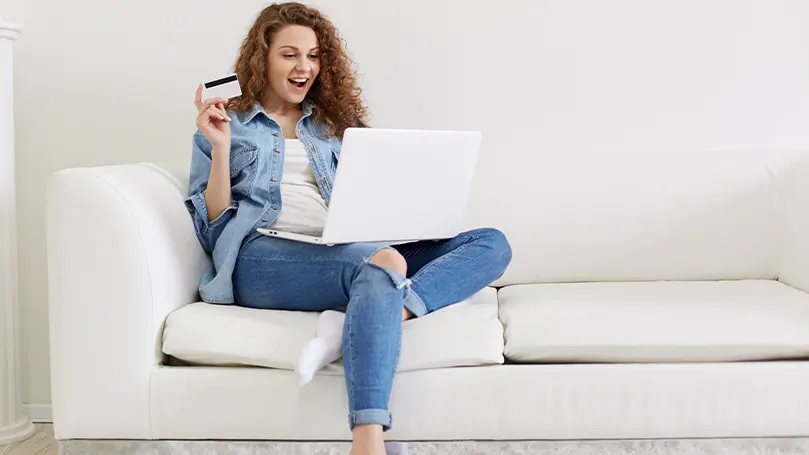 Image d'une femme assise sur le canapé et achetant quelque chose en ligne