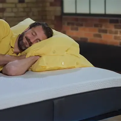 Un présentateur de Sleep Advisor dormant sur un matelas Emma Original.