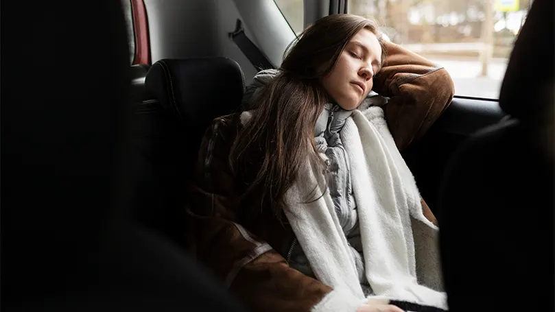 Image d'une femme dormant dans sa voiture