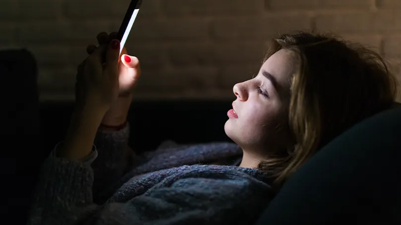 Image d'une fille regardant son téléphone au lit