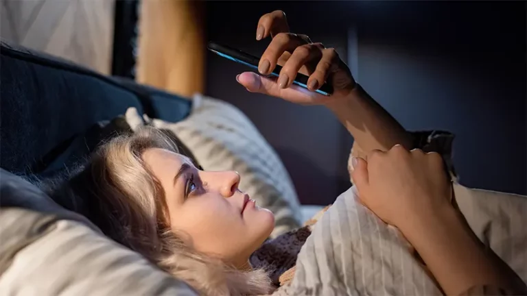 Image d'une femme au lit tenant un téléphone