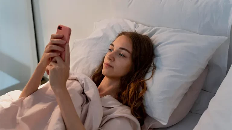 Image d'une jeune femme au lit tenant un téléphone