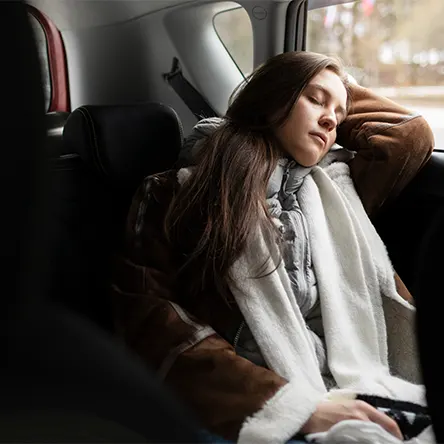 Image d'une femme dormant dans sa voiture.