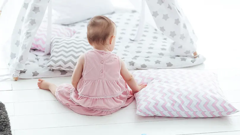 Une image d'un enfant assis à côté d'un tas d'oreillers pour jeunes enfants.