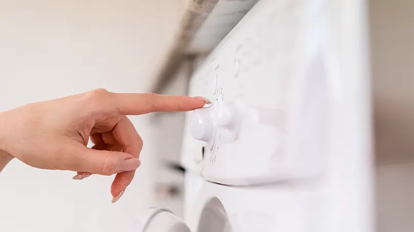 Image d'une femme mettant en marche une machine à laver