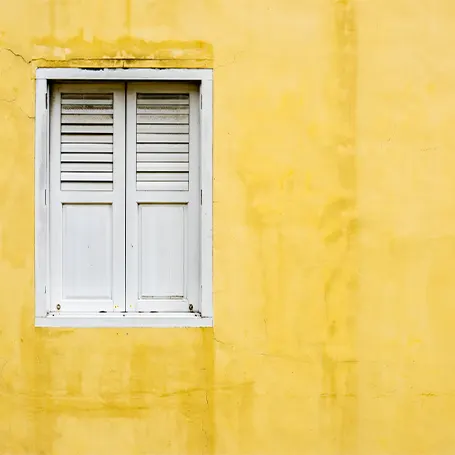 Image d'une fenêtre blanche sur un mur jaune.