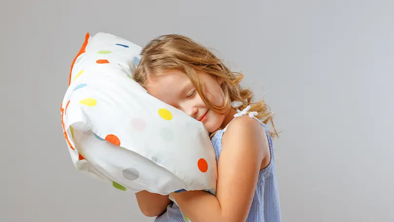 Image d'un enfant serrant son oreiller dans ses bras