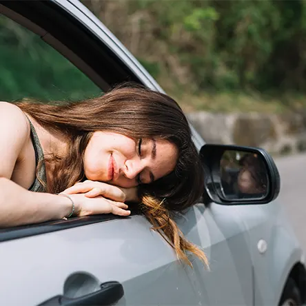 Image d'une femme dormant dans sa voiture.