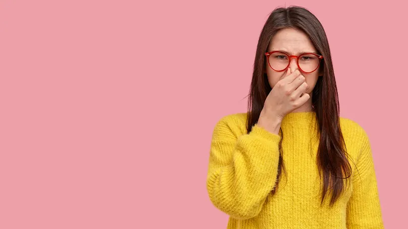 Image d'une femme se tenant le nez pour éviter une odeur désagréable.