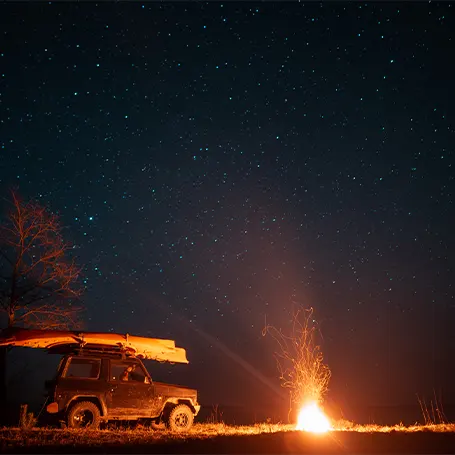 Image d'un feu de camp à côté d'une camionnette la nuit