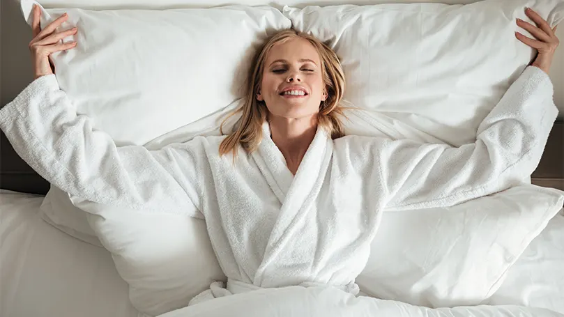 Une femme en peignoir allongée dans un lit