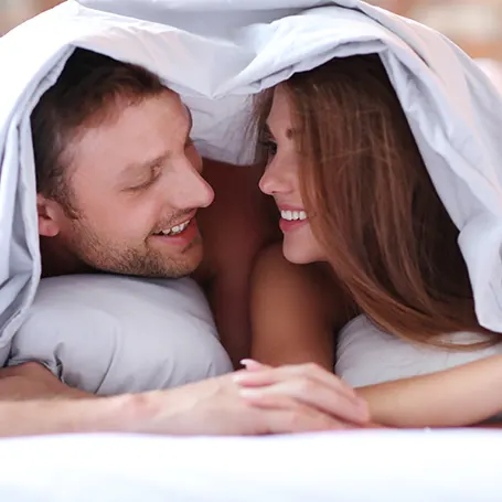 un couple dans un lit sous une couette de faible épaisseur