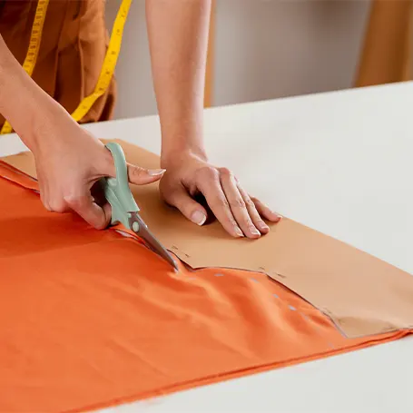 Image d'une couturière mesurant et coupant du tissu.