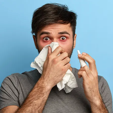 Image d'un homme souffrant d'allergies qui porte un mouchoir à son nez.