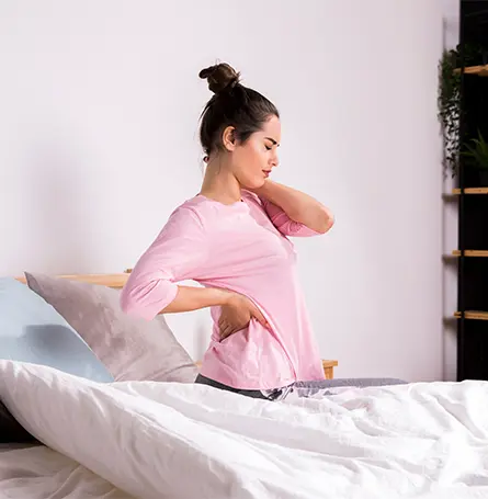 Image d'une femme au lit souffrant de douleurs dorsales