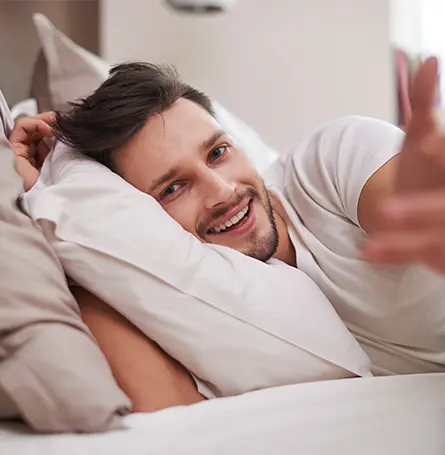 Image d'une personne souriante dans son lit le matin