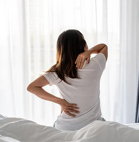 Image d'une femme au lit souffrant de douleurs dorsales
